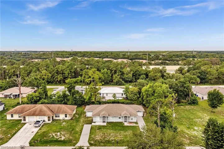 Duplex property featuring a neutral exterior, paved driveways, and surrounding green spaces