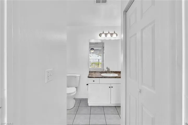 Bathroom featuring a white vanity with two-door cabinetry, a dark countertop, and a rectangular sink with a chrome faucet