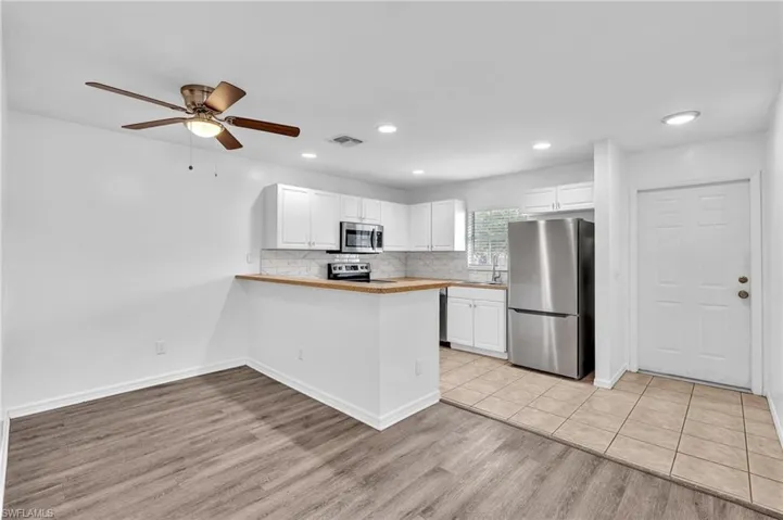 Bright kitchen featuring white cabinetry, stainless steel appliances, and wood-finish countertops