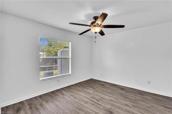 Room featuring wood-finish flooring and a ceiling fan with integrated lighting