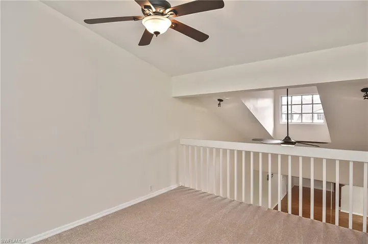 Carpeted empty room featuring lofted ceiling and ceiling fan
