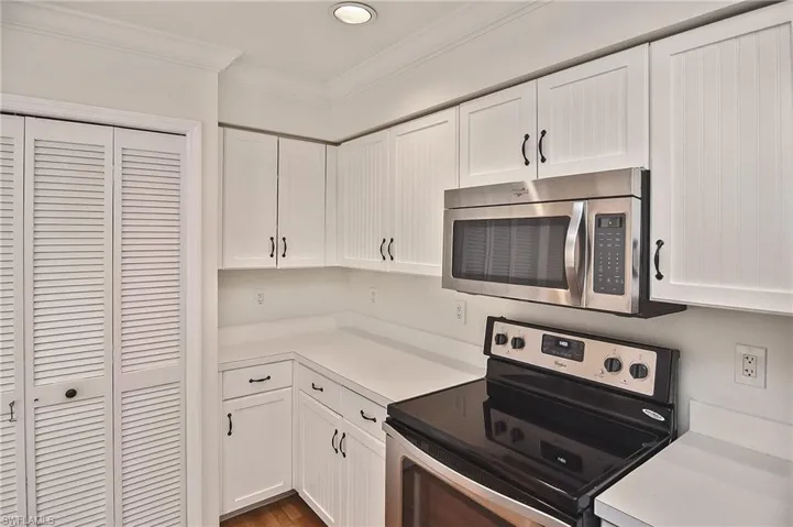 Kitchen with stainless steel appliances, white cabinets, and ornamental molding