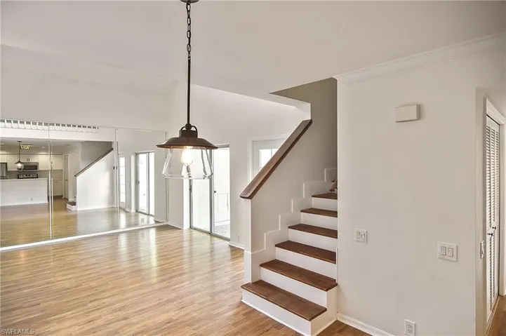Stairs with hardwood / wood-style flooring and crown molding