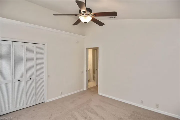 Unfurnished bedroom with a closet, lofted ceiling, light colored carpet, and ceiling fan