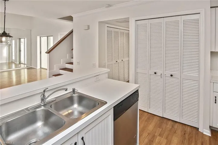 Kitchen featuring light hardwood / wood-style floors, sink, hanging light fixtures, stainless steel dishwasher, and crown molding