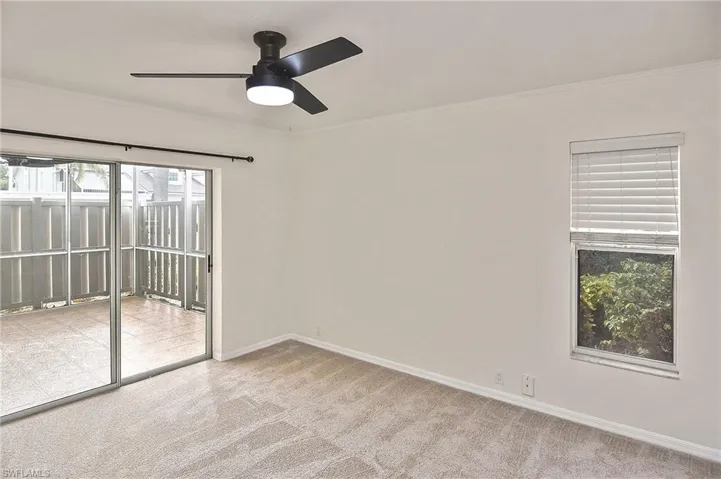 Carpeted empty room featuring ceiling fan and crown molding