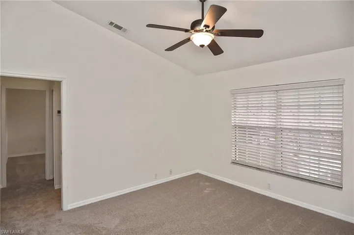 Carpeted spare room featuring lofted ceiling and ceiling fan