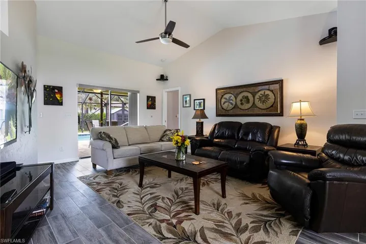 Living room with high vaulted ceiling, dark hardwood / wood-style flooring, and ceiling fan