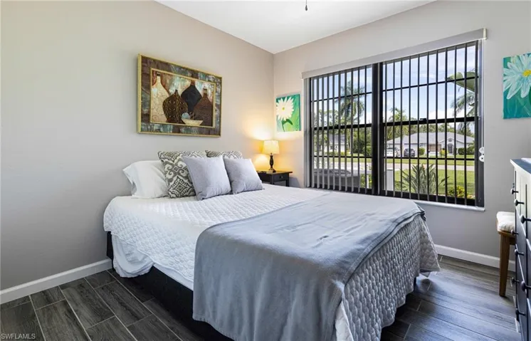 Bedroom with dark hardwood / wood-style flooring and multiple windows