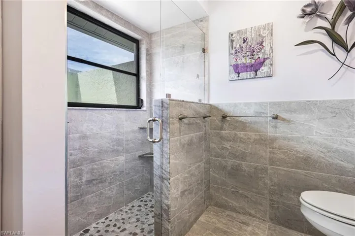 Bathroom featuring toilet and a shower with shower door