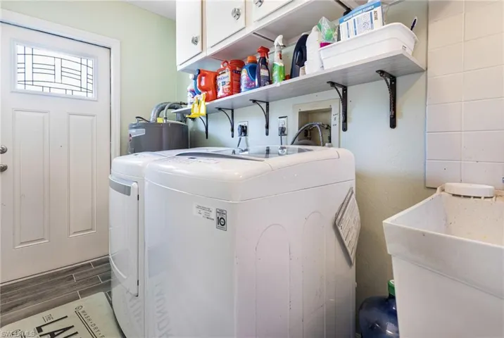 Laundry area with cabinets, washer and dryer, gas water heater, sink, and dark tile patterned floors