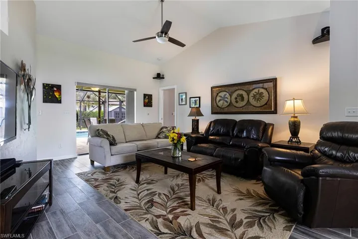 Living room featuring high vaulted ceiling, dark hardwood / wood-style floors, and ceiling fan