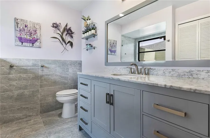Bathroom with tile walls, toilet, tile patterned floors, and vanity