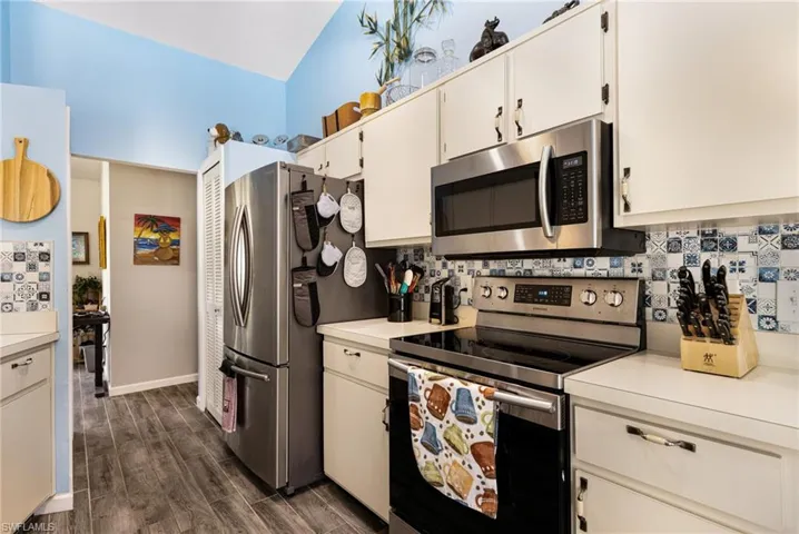 Kitchen with appliances with stainless steel finishes, backsplash, and white cabinetry