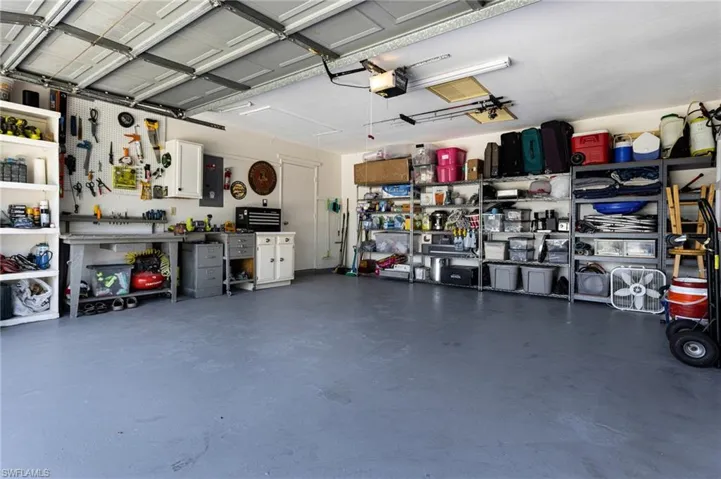 Garage with a workshop area, a garage door opener, and electric panel