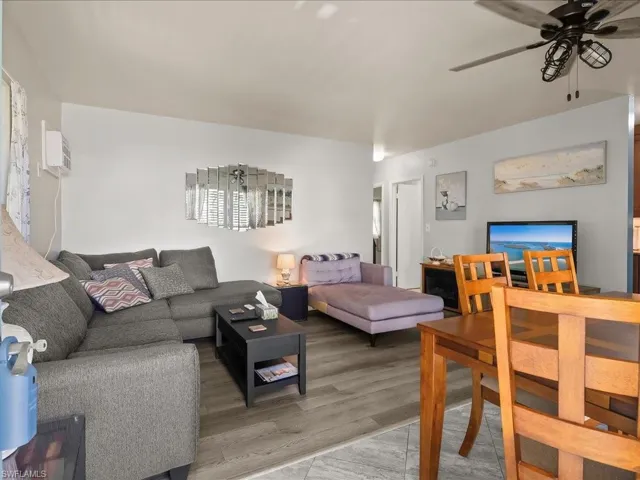 Living area with ceiling fan, wood finished floors, and a wall mounted AC