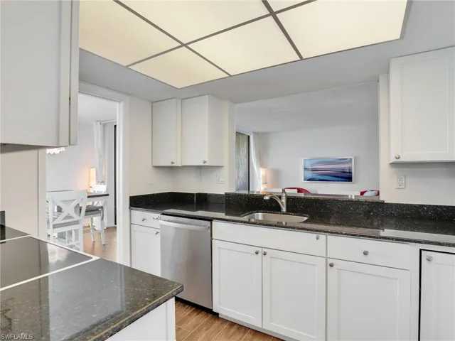 Kitchen with light wood-style floors, stainless steel dishwasher, and white cabinetry