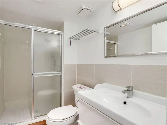 Full bath with tile walls, a stall shower, and vanity