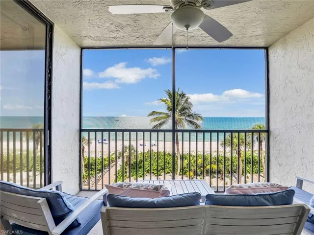Sunroom featuring ceiling fan, view of water and beach, and healthy amount of natural light