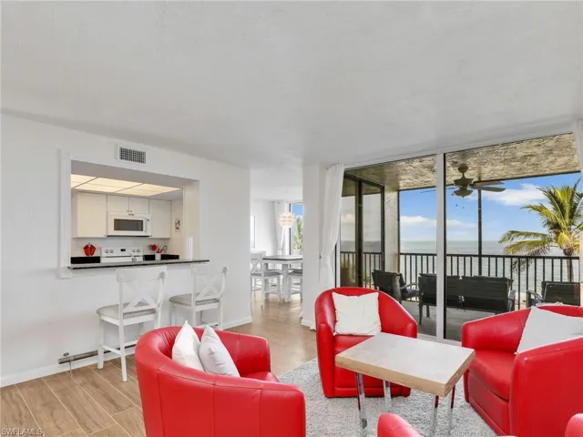 Living room featuring expansive windows, wood finished floors, a water view, and a ceiling fan