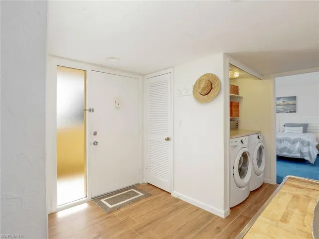 Laundry room with washing machine and clothes dryer and light wood-type flooring