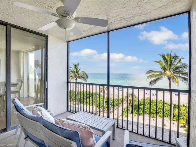 Sunroom / solarium featuring view of water and beach, a ceiling fan, and outdoor lounge area