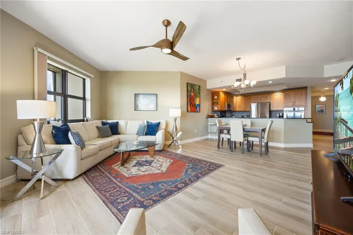 Spacious Living room with open floor plan featuring wood-like tiled floors and a ceiling fan.