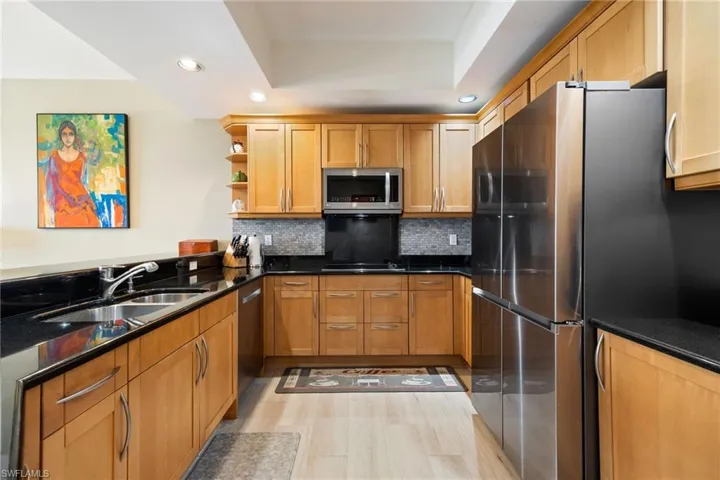 Kitchen with recessed lighting, dark granite countertops, stainless steel appliances, and decorative backsplash