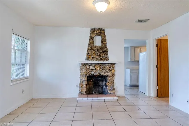 Unfurnished living room with light tile patterned floors, a textured ceiling, and a fireplace