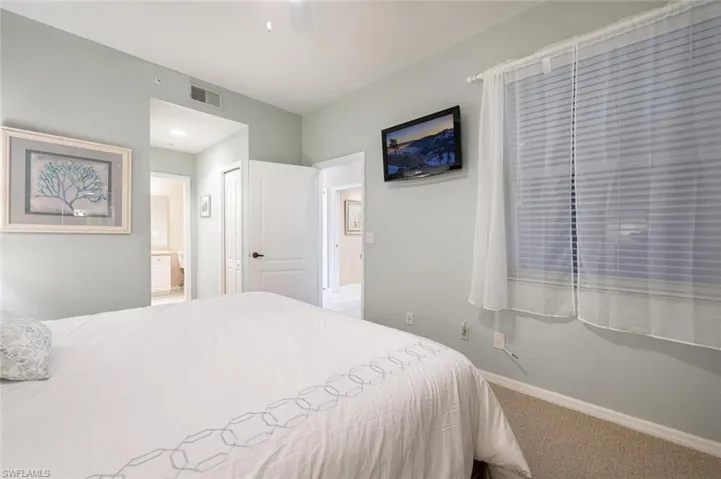 Bedroom featuring a closet, ensuite bath, ceiling fan, and carpet flooring