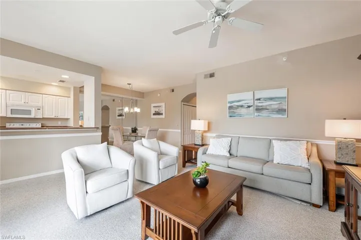 Carpeted living room featuring ceiling fan with notable chandelier