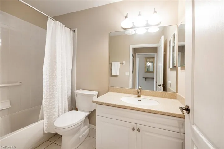 Full bathroom with shower / bath combination with curtain, tile patterned flooring, vanity, and toilet