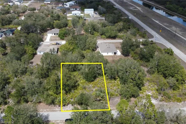 Aerial view of residential area featuring property boundaries highlighted and a nearby body of water