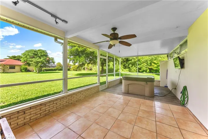 Unfurnished sunroom featuring track lighting, beamed ceiling, a wealth of natural light, and ceiling fan
