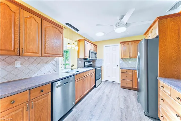 Kitchen featuring backsplash, decorative light fixtures, appliances with stainless steel finishes, and ceiling fan