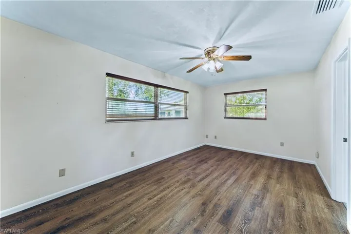 Unfurnished room with dark wood-type flooring and ceiling fan