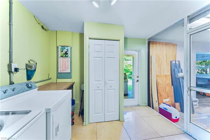 Washroom with washer and dryer and light tile patterned floors