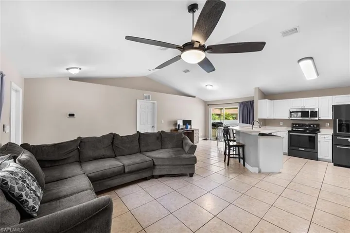 Living room featuring lofted ceiling, light tile patterned floors, and a ceiling fan