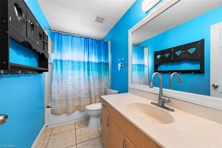 Full bath with shower / bath combination with curtain, vanity, and light tile patterned flooring