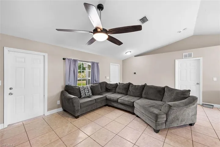 Living area featuring vaulted ceiling, light tile patterned floors, and a ceiling fan