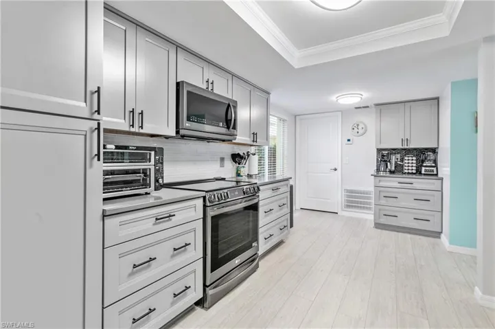 The METICULOUSLY DESIGNED KITCHEN is a true HIGHLIGHT, featuring soft-close, light-gray cabinets, stunning quartz countertops