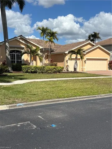 View of front of property featuring stucco siding, a front lawn, a tile roof, driveway, and an attached garage