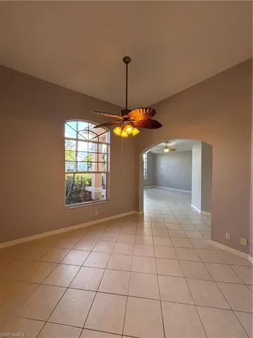 Dining room featuring ceiling fan, arched walkways, and vaulted ceiling.