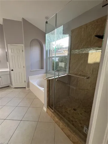 Full bath with a bathtub, separate shower stall, lofted ceiling, 2 vanities and a water closet