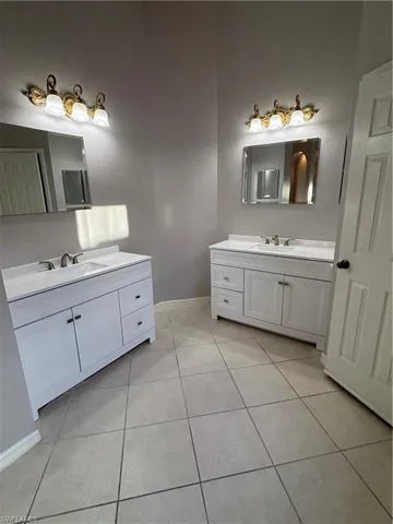 Full bathroom featuring light tile patterned floors and two new vanities, mirrors and medicine cabinets