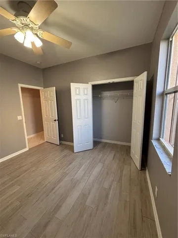 Bedroom featuring a ceiling fan, light wood-style tile flooring, and double doors closet