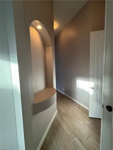 Primary Suite Hallway with light wood-style tile floors and vaulted ceiling