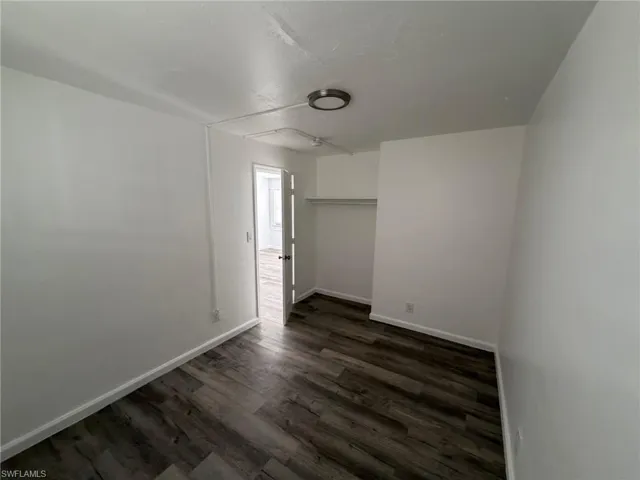 Unfurnished bedroom featuring dark wood finished floors and a closet