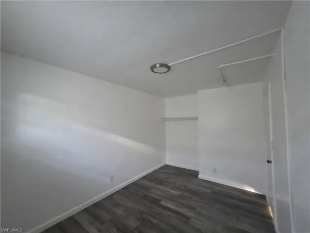 Unfurnished bedroom featuring dark wood-type flooring and a closet