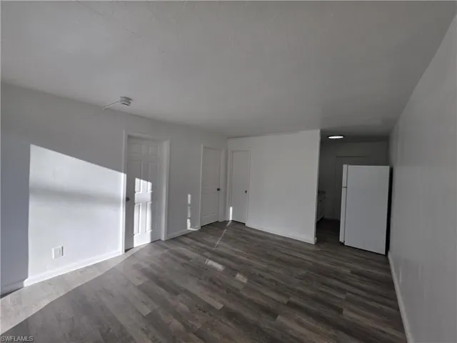 Empty room featuring dark wood-style floors and baseboards